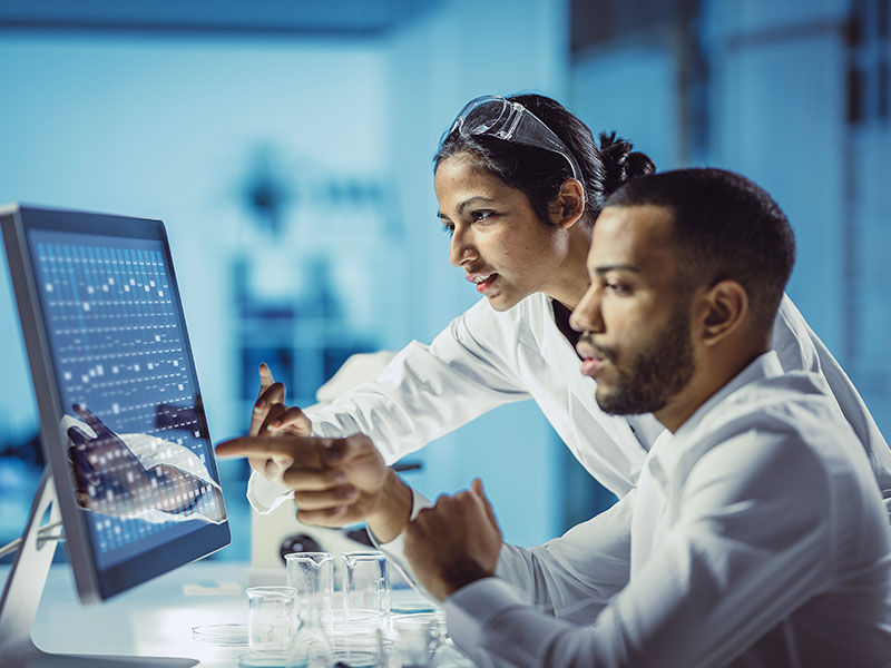 Two scientists pointing at screen in lab
