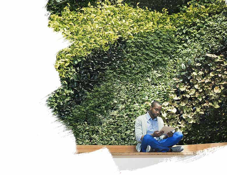 Sitting man looking at tablet in front of a green wall